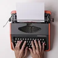Hands of an author on an old-fashioned typewrite writing a document